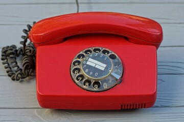 landline, rotary with dialer plastic old classic red office with black wire telephone stands on a gray wooden table - obrazy, fototapety, plakaty