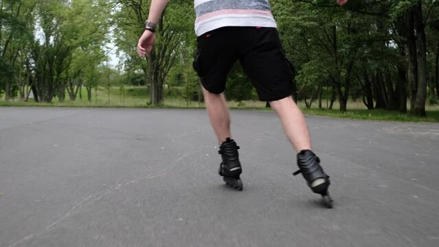 Young man practicing rollerscating in park at summer. Guy wearing roller scate enjoying outdoot activities and riding professionally