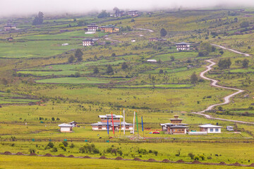 View of green valley with clouds over mountains in the background located in Bhutan.