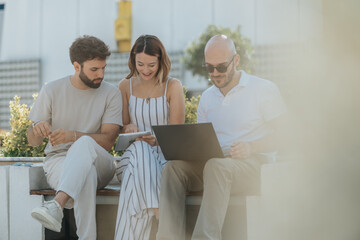 A team of adults discusses architectural designs and blueprints outdoors, working together on a modern project.