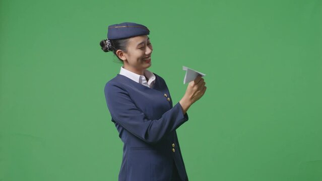 Asian Woman Air Hostess In Professional Uniform Launching Paper Plane, Holding Jet Model In Hands, Aviation Academy Aviator, Aircraft Captain On Green Screen Background Studio
