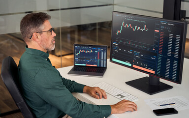 Busy middle aged older business man financial investor, stock trader broker analyzing online finance digital market thinking of investment strategy in crypto trading exchange platform using computer.