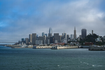 Obraz premium Sunny day over San Francisco Bay with port piers, city skyline downtown architecture highrise buildings and landmarks seen from Harbor Cruise ship