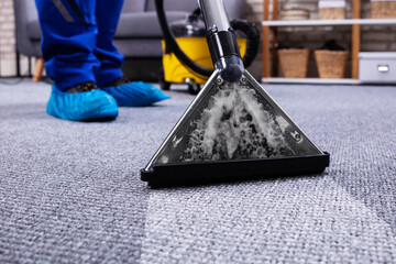 Person Cleaning Carpet With Vacuum Cleaner