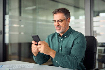 Busy smiling business man executive of mid age looking at smartphone digital technology, older...
