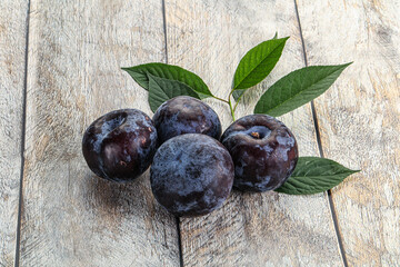 Raw purple plums heap with leaves