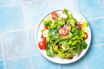 Green vegetable salad with fresh leaves on white plate. Healthy food, diet menu. Top view with space for text.