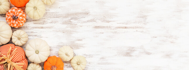 Autumn farmhouse pumpkin corner border over a white wood banner background. Rustic orange and white cloth pumpkins. Top down view with copy space.