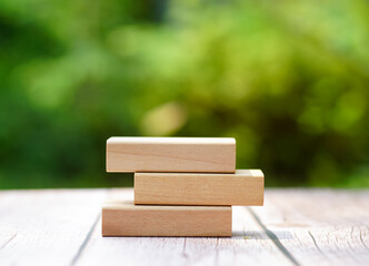 3 stacking rectangle empty wooden blocks on table with green natural blur background for own customer text or letters. Idea of environment, energy or business concept. Front view, banner copy space.