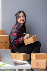 Startup happy Asian woman sme business owner work with prepare parcel delivery boxs at home, SME supply chain, procurement, package box to deliver to customers, Online SME business entrepreneurs ideas