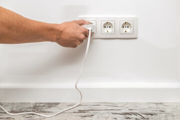 Man plugging phone adapter into a electrical outlet.