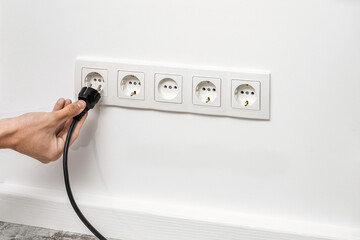 Man unplugging cord from a electrical outlet.