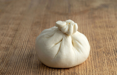 A head of typical Italian cow's milk Burrata cheese on a wooden background. Selective focus.