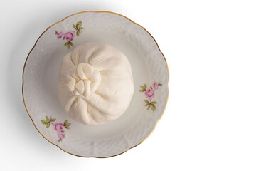 Burrata cheese on a porcelain saucer. Isolated on white background. Selective focus..