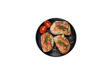Toast sandwich with butter, avocado and salmon, decorated with arugula and sesame seeds, on a black stone background