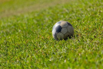 Balón de fútbol desgastado sobre el pasto de una soleada cancha de fútbol © bladiavila