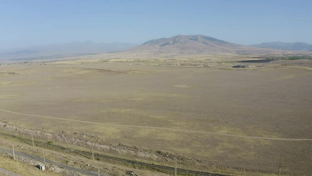Backward reveal aerial shot of apple plantation on the background of Ara and Aragats mountains on sunny summer day. Mrgashen village, Armenia.