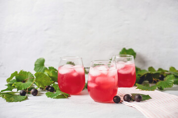Three Glasses of Muscadine Lemonade with Muscadines and Vines in the Background on a White Surface