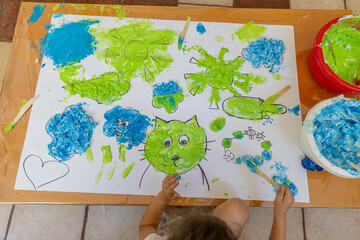 the girl drew a picture using multi-colored foam: a cat’s face and clouds