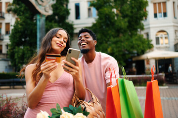 Young couple is doing shopping via smartphone outdoors