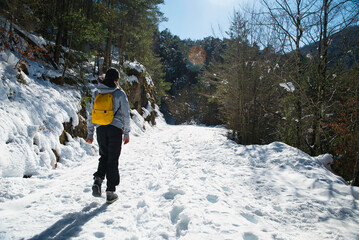 Adventurous girl enjoying hiking in the middle of nature during the winter season with snow...