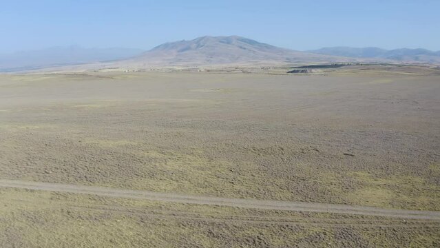 Bacward reveal aerial shot of apple plantation and railroad on the background of Ara and Aragats mountains on sunny summer day. Mrgashen village, Armenia.