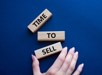 Time to Sell symbol. Concept words Time to Sell on wooden blocks. Businessman hand. Beautiful deep blue background. Business and Time to Sell concept. Copy space.
