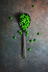 Top View of Green Peas in a Spoon on a Black Background