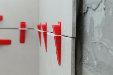 Flat wall plastic tile leveling system. Process of installation of tiles in the bathroom step by...