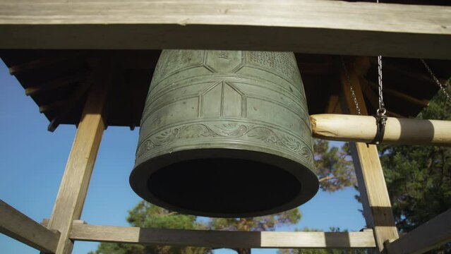 Log hitting the old Japanese temple bell at the Japanese Gardens. Slow motion. 