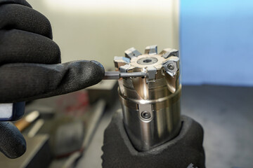 A worker changes a high speed insert on a milling cutter to work on a CNC milling machine.