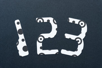numbers 1, 2, 3 cut from black and white paper with spots or rings and dots on black