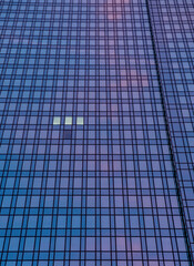 modern office building at dusk with the reflection of pink clouds on the glass window and few lights in the office near Frankfurt, Germany