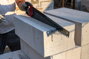 The process of sawing aerated concrete blocks with a hand saw. Construction of aerated concrete bricks, blocks.