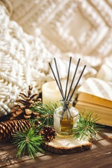 Christmas home aromatherapy. Aroma diffuser with pine extract, organic essential oil, cedar and spruce cone, candles on wooden table. Cozy atmosphere, holiday spirit. Winter inspiration and mood.