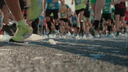Group of runners run towards the camera, crossing starting line of city marathon. Fit and active participants push their boundaries and test their endurance. Healthy and athletic spirit. 