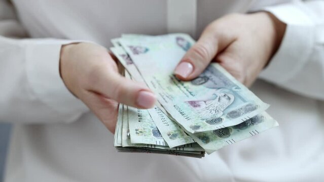 Woman Counting AED Dirhams in hands, closeup