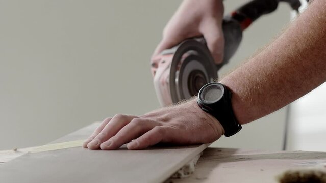 Professional tiler cutting tile with angle grinder.