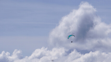 A paragliding flying in sky among clouds  