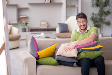 Young man with a lot of pillows sitting on the sofa