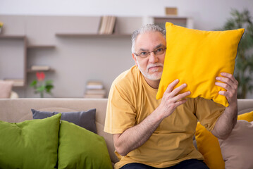 Fototapeta premium Old man with many pillows at home