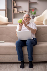 Old man holding piggybank at home