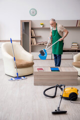 Old male contractor cleaning the house