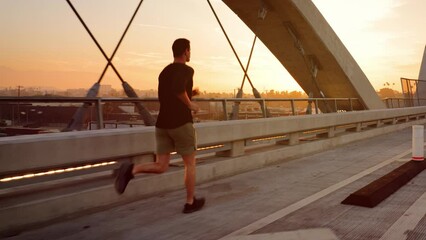 Athletic Man working out by jogging across the 6th Street Bridge over the LA River near downtown Los Angeles at dawn.