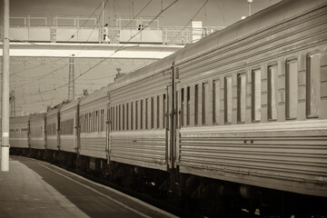 Fototapeta premium A long-distance passenger train made a stop in a small town, photographed in clear weather in summer, Ukraine.