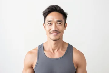 Fotobehang Portrait photography of a Vietnamese man in his 30s wearing a sporty tank top against a white background © Anne Schaum