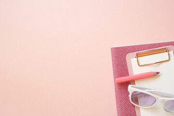 Pink notebook, clipboard, colored pencil, eyeglasses on pink desk background. flat lay, top view, copy space. workspace