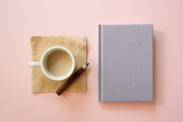 Cup of coffee and diary notebook, colored pencil isolated on pink background. top view, copy space