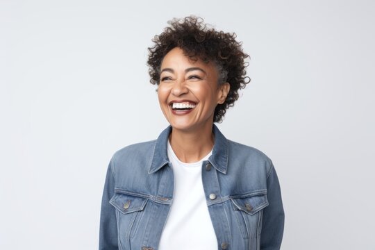 Portrait photography of a Colombian woman in her 50s wearing a denim jacket against a white background