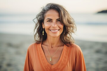 Medium shot portrait photography of a Colombian woman in her 50s wearing a simple tunic against a beach background